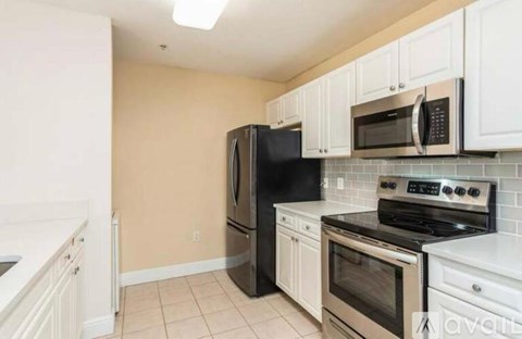 A kitchen with white cabinets and black appliances.