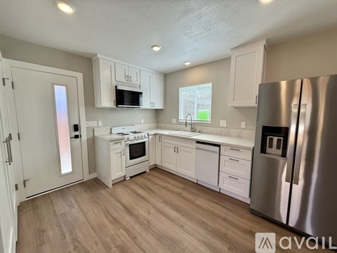 A kitchen with white cabinets and a stainless steel refrigerator.