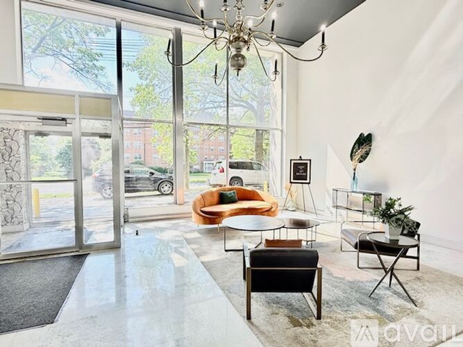 A living room with a chandelier, a sofa, a chair, a coffee table, and a potted plant.