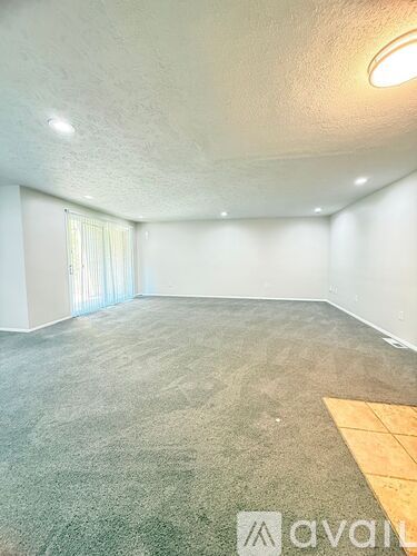 A room with a carpeted floor and a window with blinds.