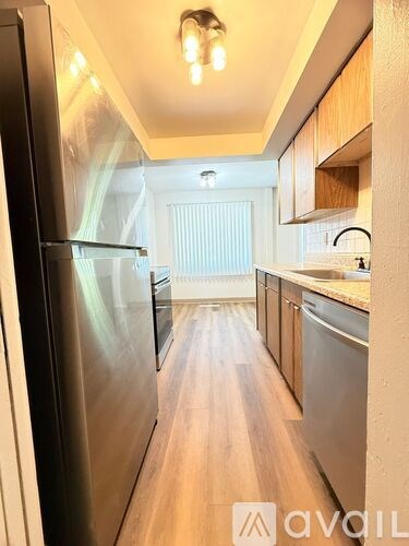 A kitchen with wooden cabinets and a stainless steel refrigerator.