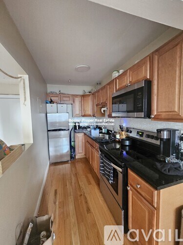 A kitchen with wooden cabinets and black countertops.