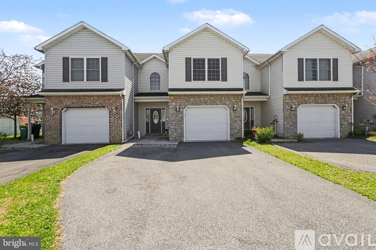 A large, two-story house with a driveway in front.