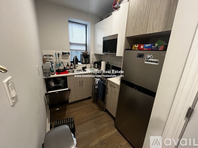 A kitchen with a refrigerator, stove, and cabinets.