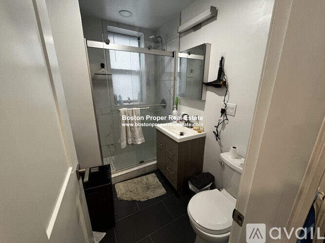A bathroom with a toilet, sink, and mirror.