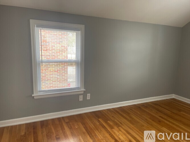 A room with a wooden floor and a window with blinds.