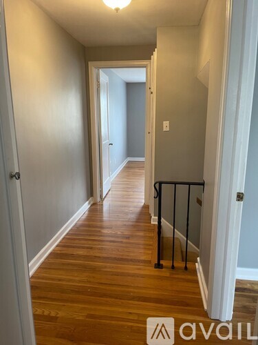 A hallway with wood floors and white walls.
