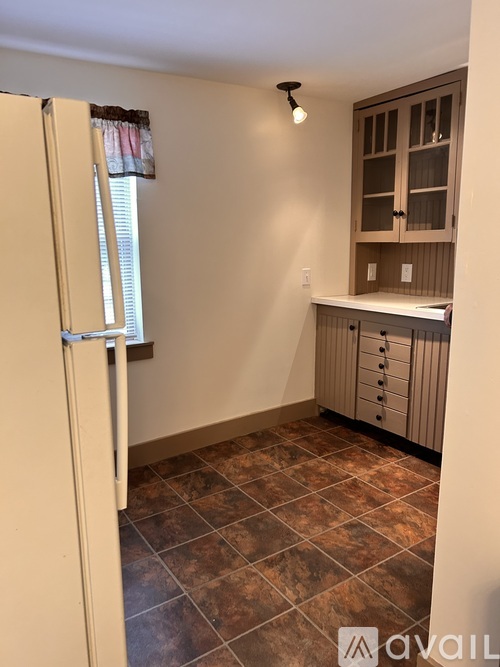 A kitchen area with a refrigerator, cabinets, and a countertop.