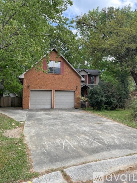 A red brick house with a garage door and a driveway.