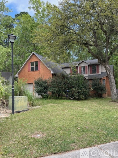 A house with a red brick exterior and a green lawn.