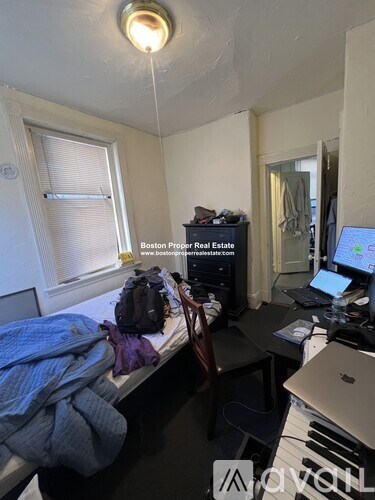 A small room with a bed, desk, and laptop.