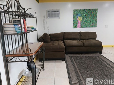 A living room with a brown couch and a painting on the wall.