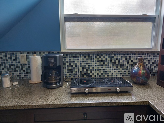 A kitchen counter with a coffee maker, a griddle, and a vase.