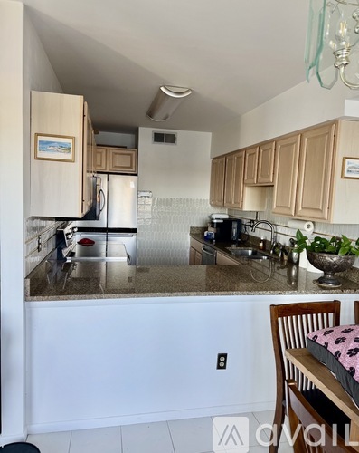 A kitchen with a refrigerator, sink, and cabinets.