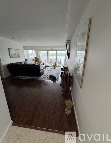 A living room with a black couch and a painting on the wall.