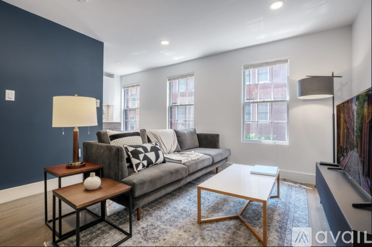 A living room with a grey couch, a wooden coffee table, and a lamp.