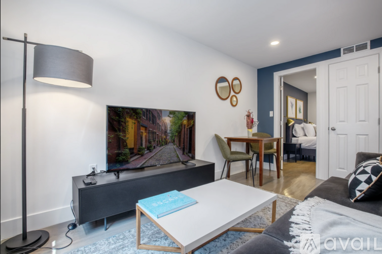 A living room with a grey sofa, a white coffee table, and a television on a cabinet.