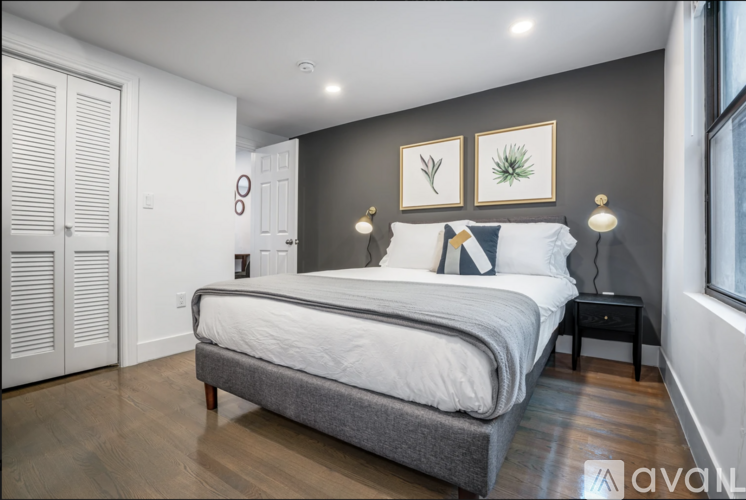 A bedroom with a large bed and a wooden floor.