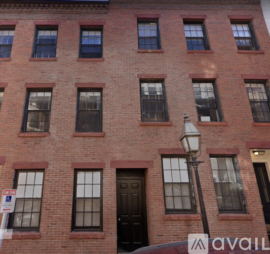 A red brick building with a black door and a lamp post in front.