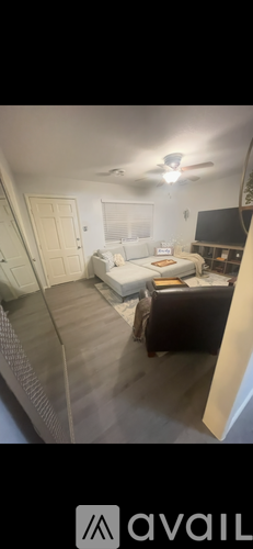 A room with a bed, a desk, and a ceiling fan.