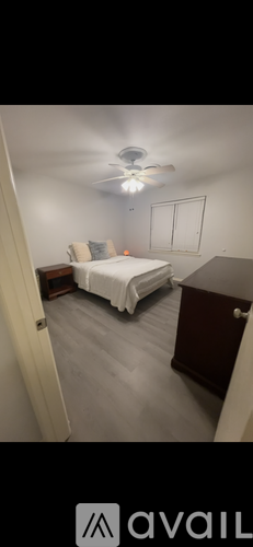 A bedroom with a bed, dresser, and ceiling fan.