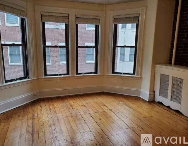 A room with wooden floors and three windows.