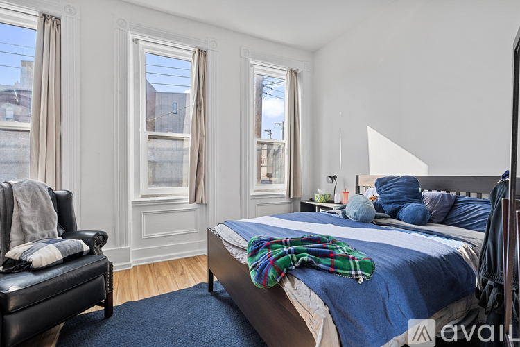 A bedroom with a bed, chair, and window.
