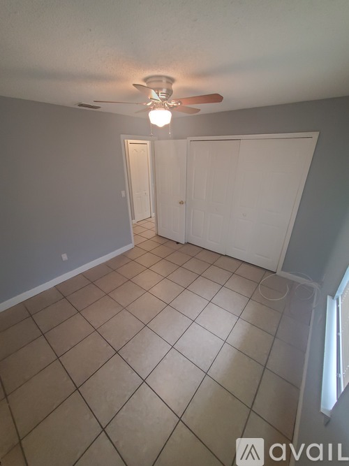 A room with a ceiling fan and tile flooring.