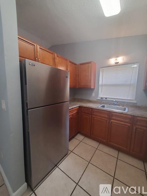 A kitchen with a refrigerator and wooden cabinets.