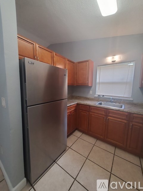 A kitchen with a refrigerator and wooden cabinets.