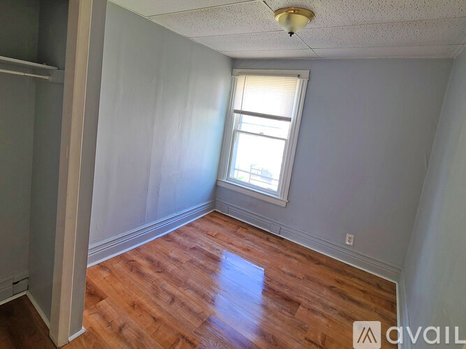 A room with wooden floors and a window with blinds.