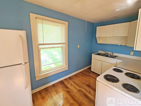 A kitchen with a white stove and a window with blinds.