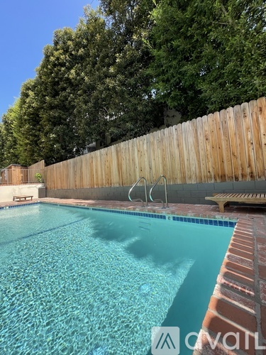 A pool with a wooden fence and trees in the background.
