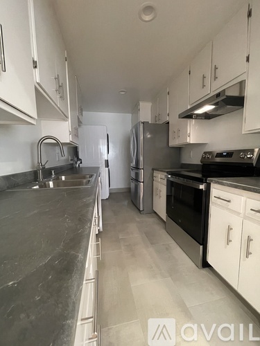 A kitchen with white cabinets and a marble countertop.