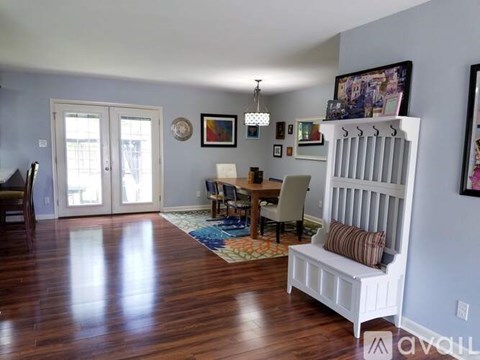 A living room with a white bench and a dining table with chairs.