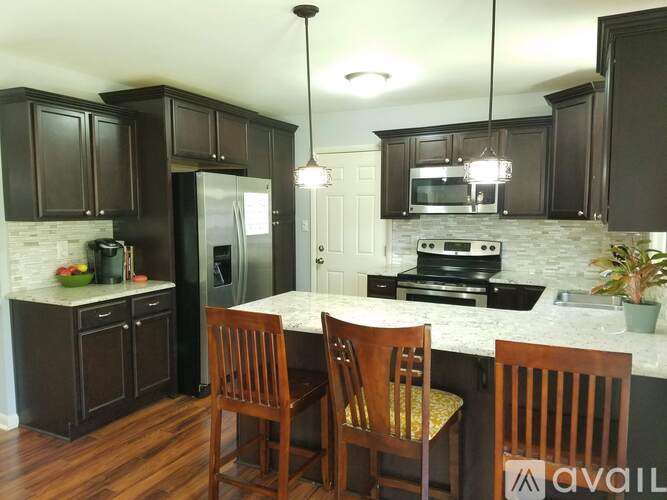A kitchen with dark brown cabinets and a white countertop.