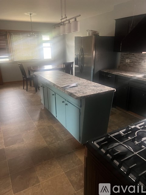 A kitchen with a blue island and a stove top oven.
