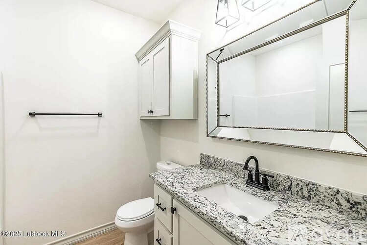 A bathroom with a toilet, sink, and mirror.
