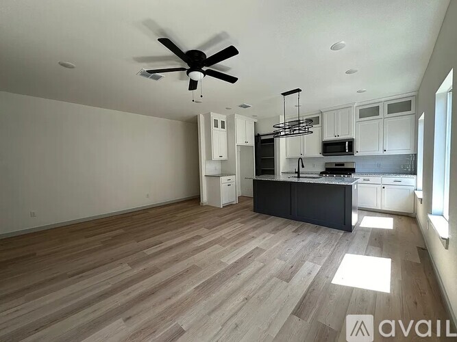 A spacious kitchen with a ceiling fan and wooden flooring.