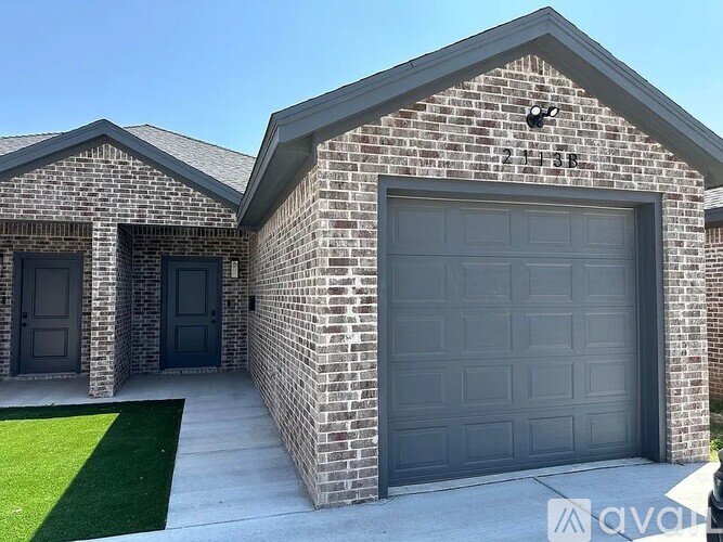 A house with a grey garage door and a brick exterior.