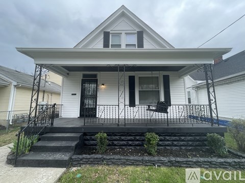 A white house with a black front porch and stairs.