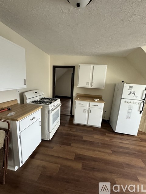 A kitchen with white appliances and wooden floors.