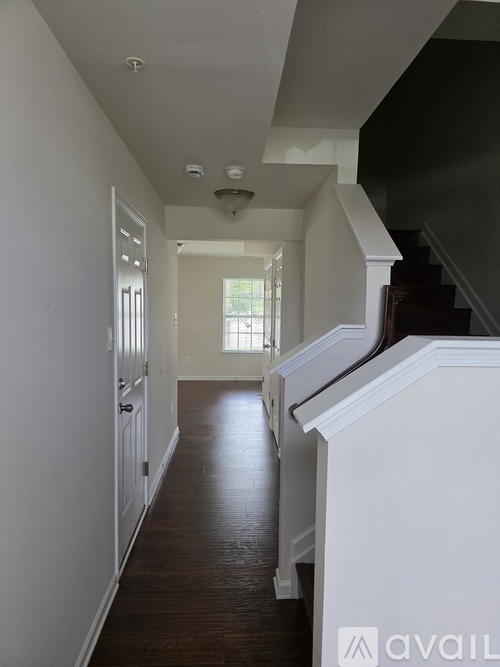 A long hallway with white walls and wood floors.