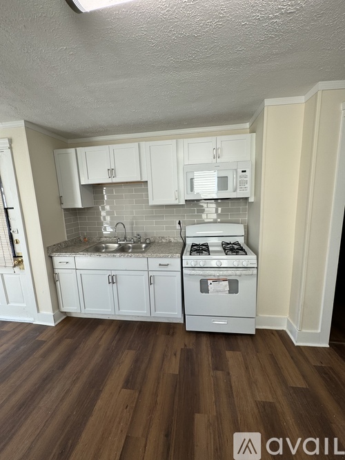 A kitchen with white cabinets and a wooden floor.