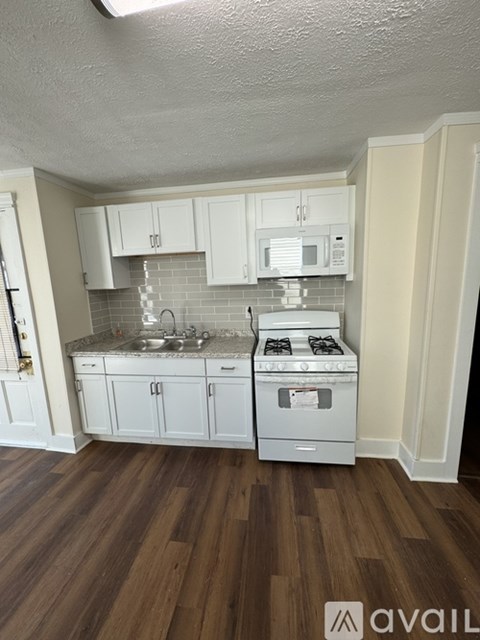 A kitchen with white cabinets and a wooden floor.