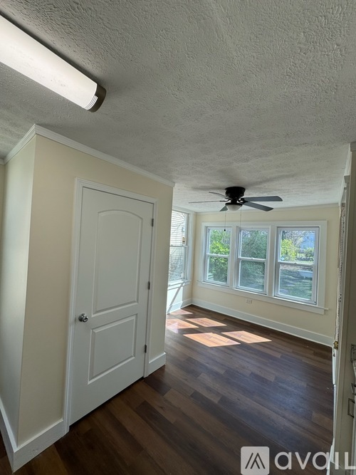 A room with a ceiling fan and a door leading to another room.