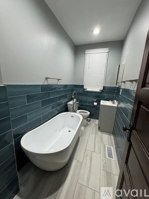 A modern bathroom with a white bathtub and a window.