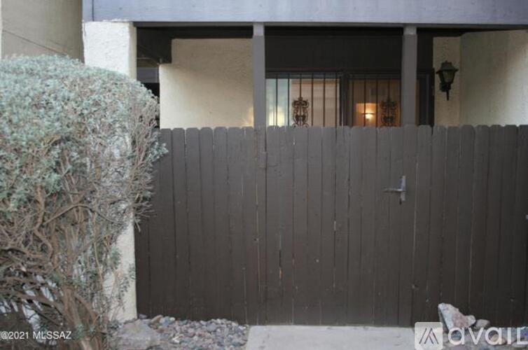 A grey fence in front of a building with a window.