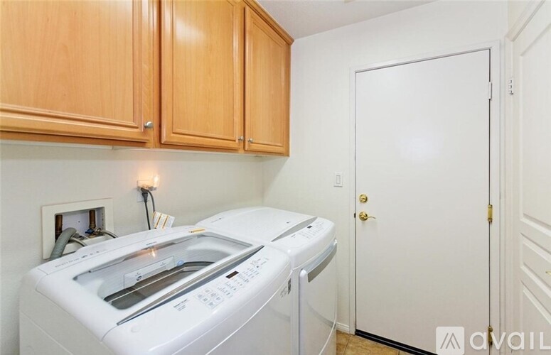 A white washing machine is in a kitchen with wooden cabinets.
