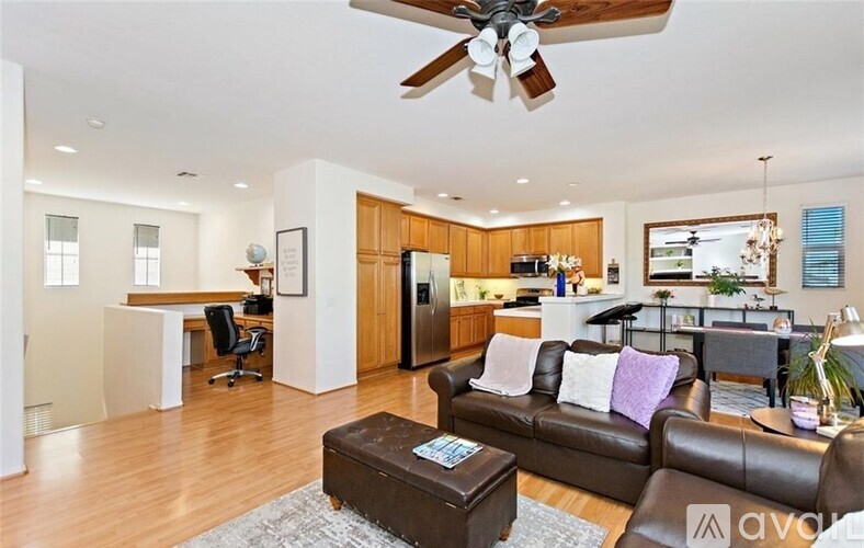 A living room with a brown couch and a ceiling fan.